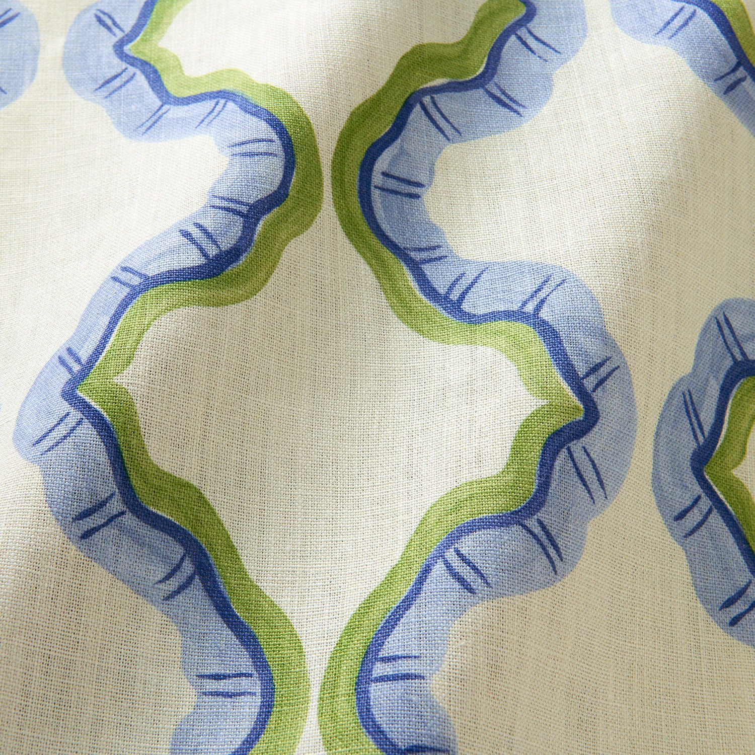 A printed linen fabric sample in blue, green, and off white featuring a mirrored ribbon pattern.