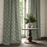 Curtains made from a printed linen fabric in blue, black, and off white featuring a mirrored ribbon pattern.