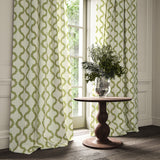 Curtains made from a printed linen fabric in green, brown, and off white featuring a mirrored ribbon pattern.