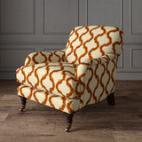 Armchair upholstered in a printed linen fabric in orange, brown, and off white featuring a mirrored ribbon pattern.