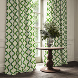 Curtains made from a printed linen fabric in green, blue, and off white featuring a mirrored ribbon pattern.
