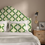 Headboard upholstered in a printed linen fabric in green, blue, and off white featuring a mirrored ribbon pattern.