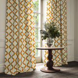 Curtains made from a printed linen fabric in blue, orange, and off white featuring a mirrored ribbon pattern.