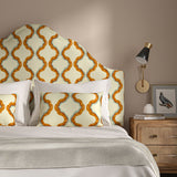 Headboard upholstered in a printed linen fabric in blue, orange, and off white featuring a mirrored ribbon pattern.