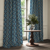 Curtains made from a printed linen fabric in blue, black, and off white featuring a mirrored ribbon pattern.