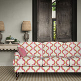 Sofa upholstered in a printed linen fabric in pink, yellow, and off white featuring a mirrored ribbon pattern.