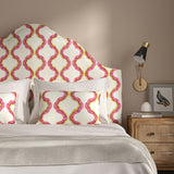 Headboard upholstered in a printed linen fabric in pink, yellow, and off white featuring a mirrored ribbon pattern.