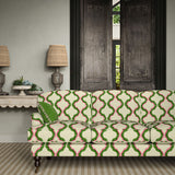 Sofa upholstered in a printed linen fabric in pink, green, and off white featuring a mirrored ribbon pattern.
