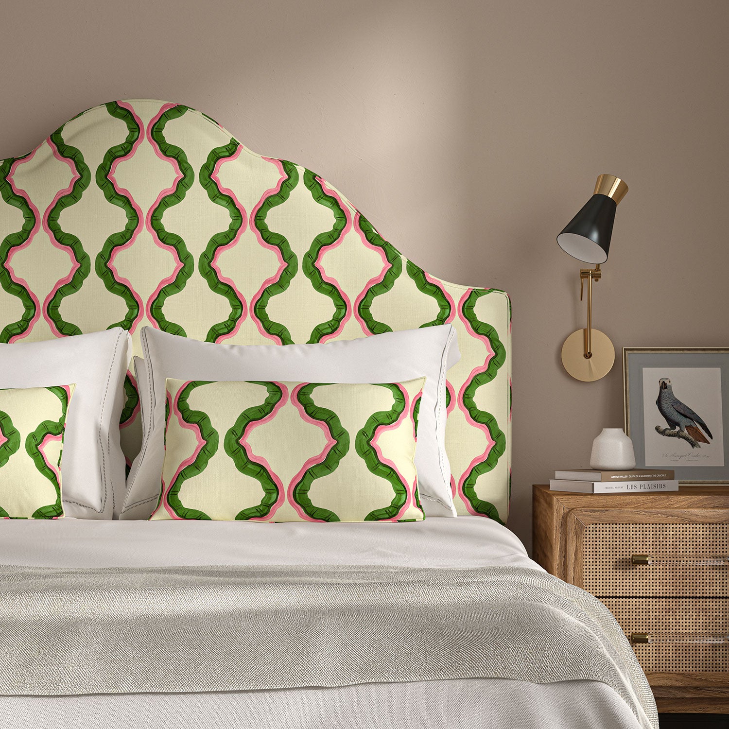 Headboard upholstered in a printed linen fabric in pink, green, and off white featuring a mirrored ribbon pattern.