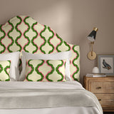 Headboard upholstered in a printed linen fabric in pink, green, and off white featuring a mirrored ribbon pattern.