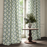 Curtains made from a printed linen fabric in blue, green, and off white featuring a mirrored ribbon pattern.