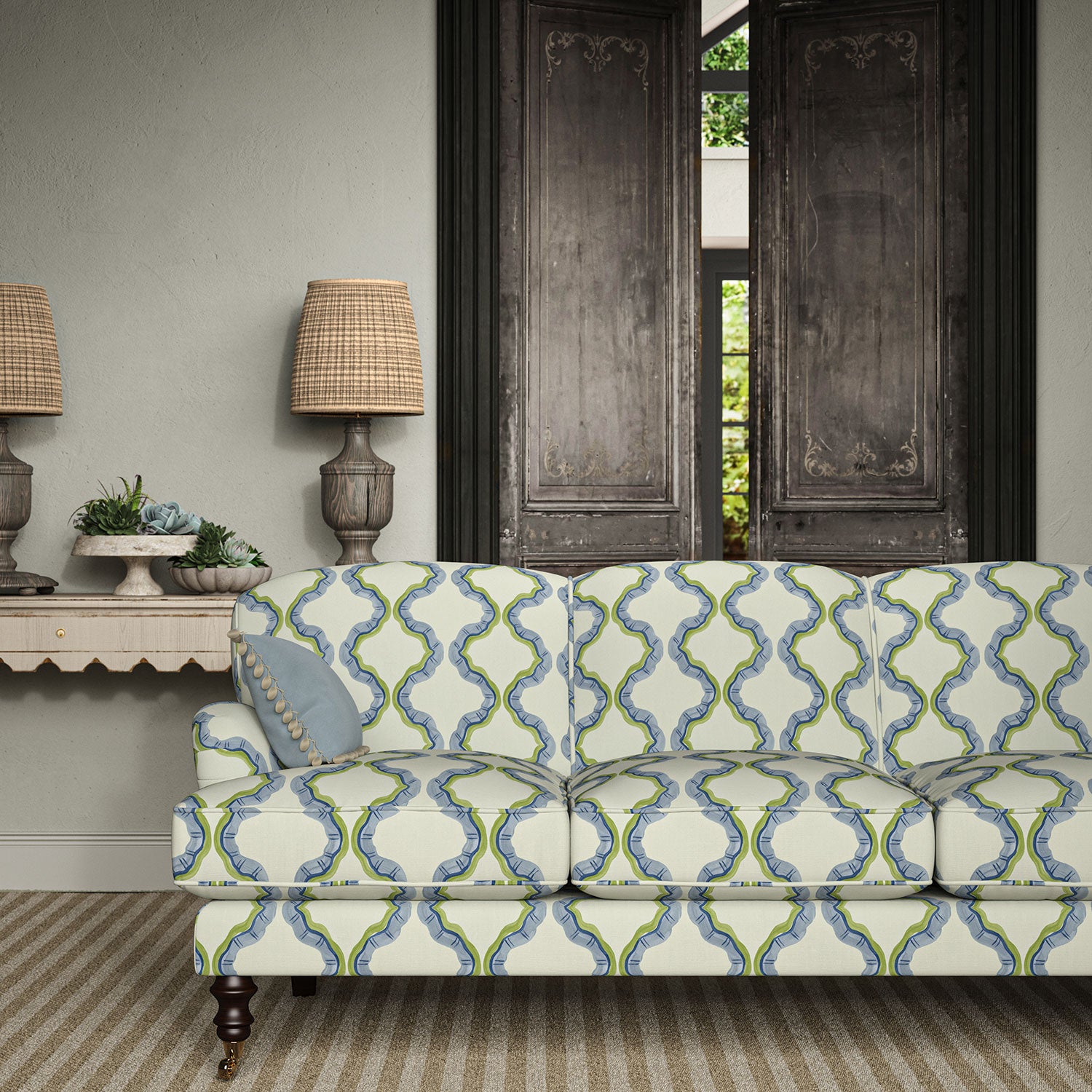 Sofa upholstered in a printed linen fabric in blue, green, and off white featuring a mirrored ribbon pattern.