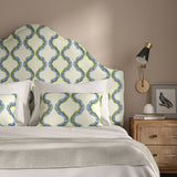 Headboard upholstered in a printed linen fabric in blue, green, and off white featuring a mirrored ribbon pattern.