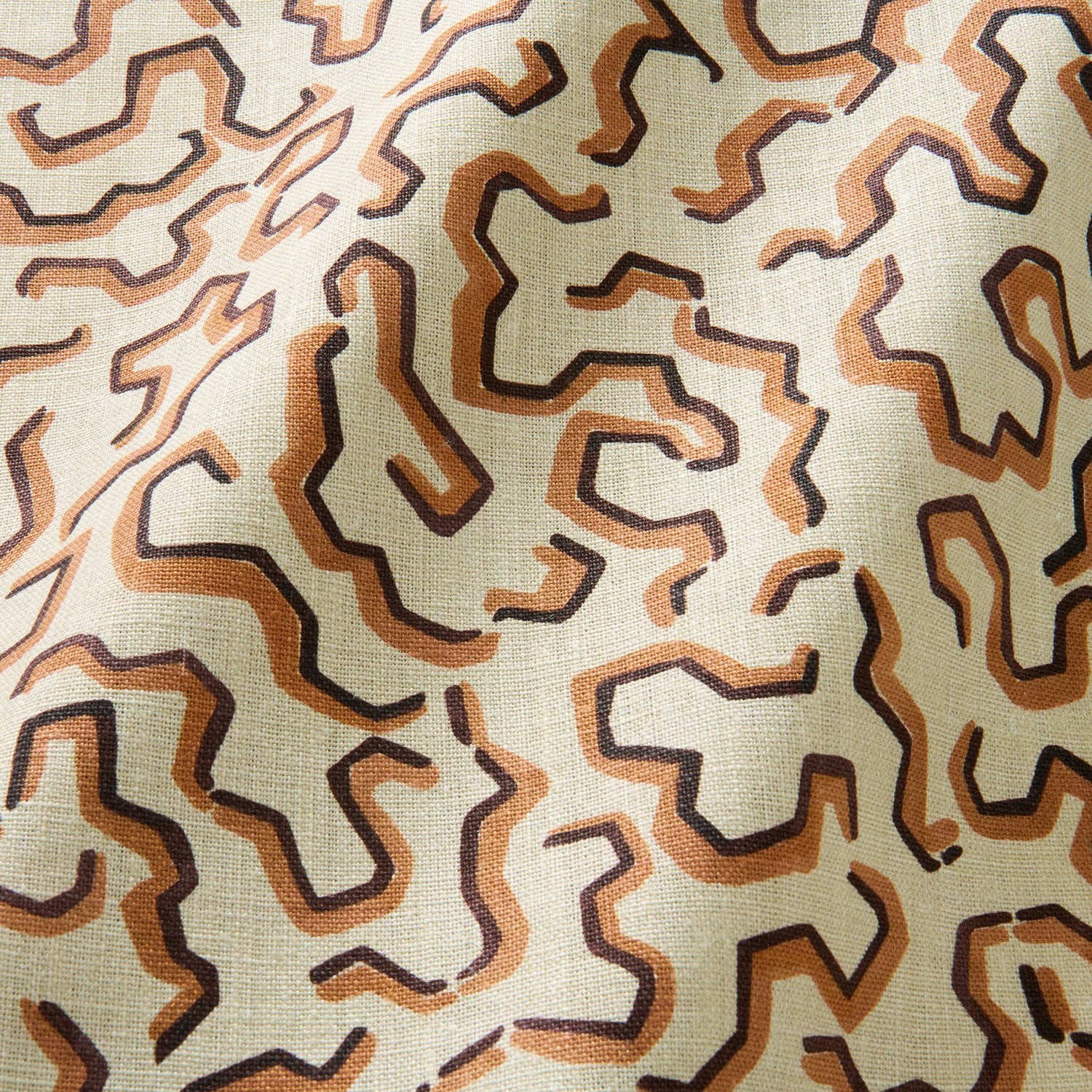 A printed linen fabric sample in brown, orange, and off white featuring a feel of a classic animal print.