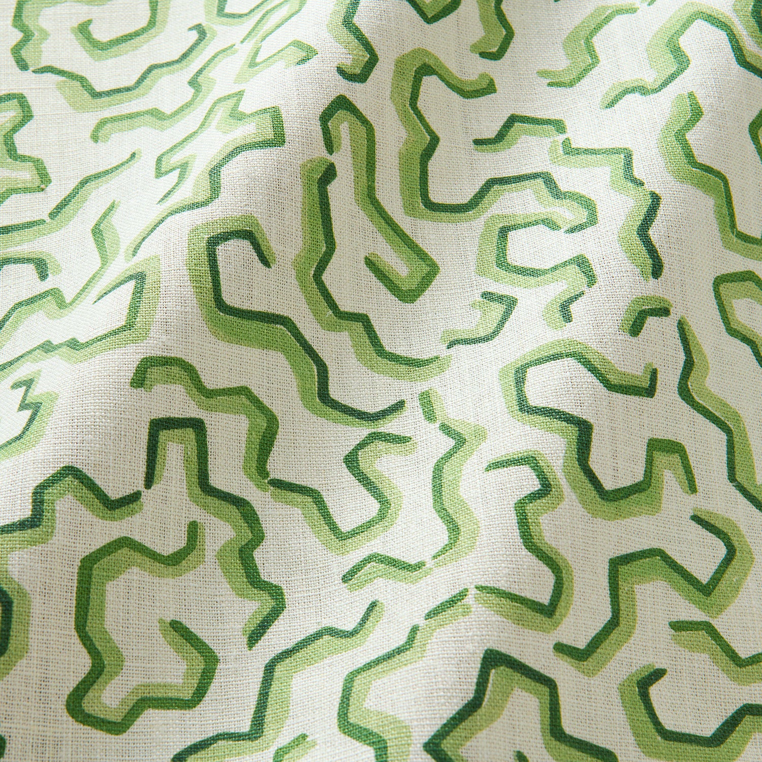 A printed linen fabric sample in green and off white featuring a feel of a classic animal print.