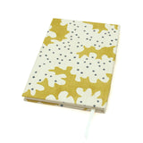 A yellow and cream linen notebook with a stylized coral pattern.