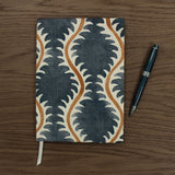 A blue, brown and cream linen notebook with a classic trellis pattern.