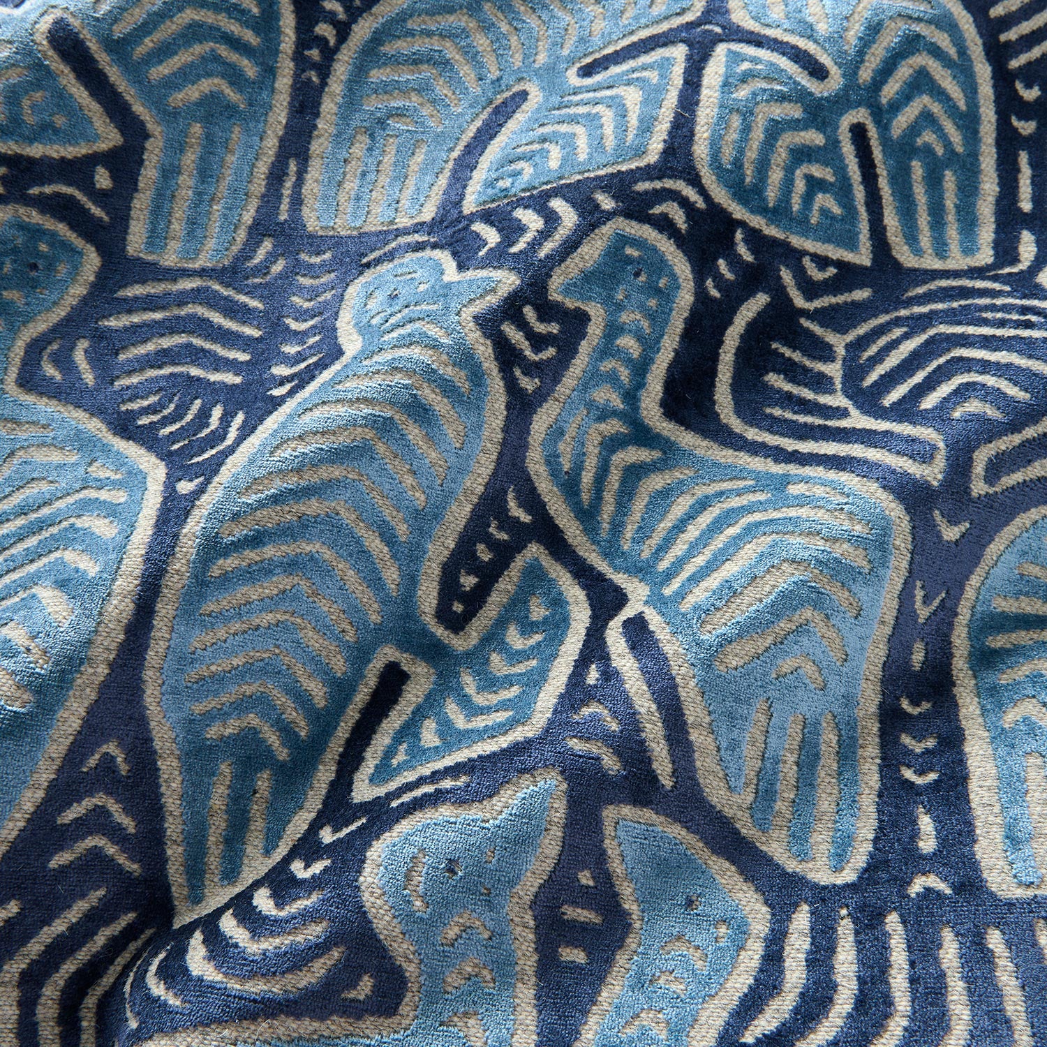 A woven velvet sample in blue and cream featuring two birds.