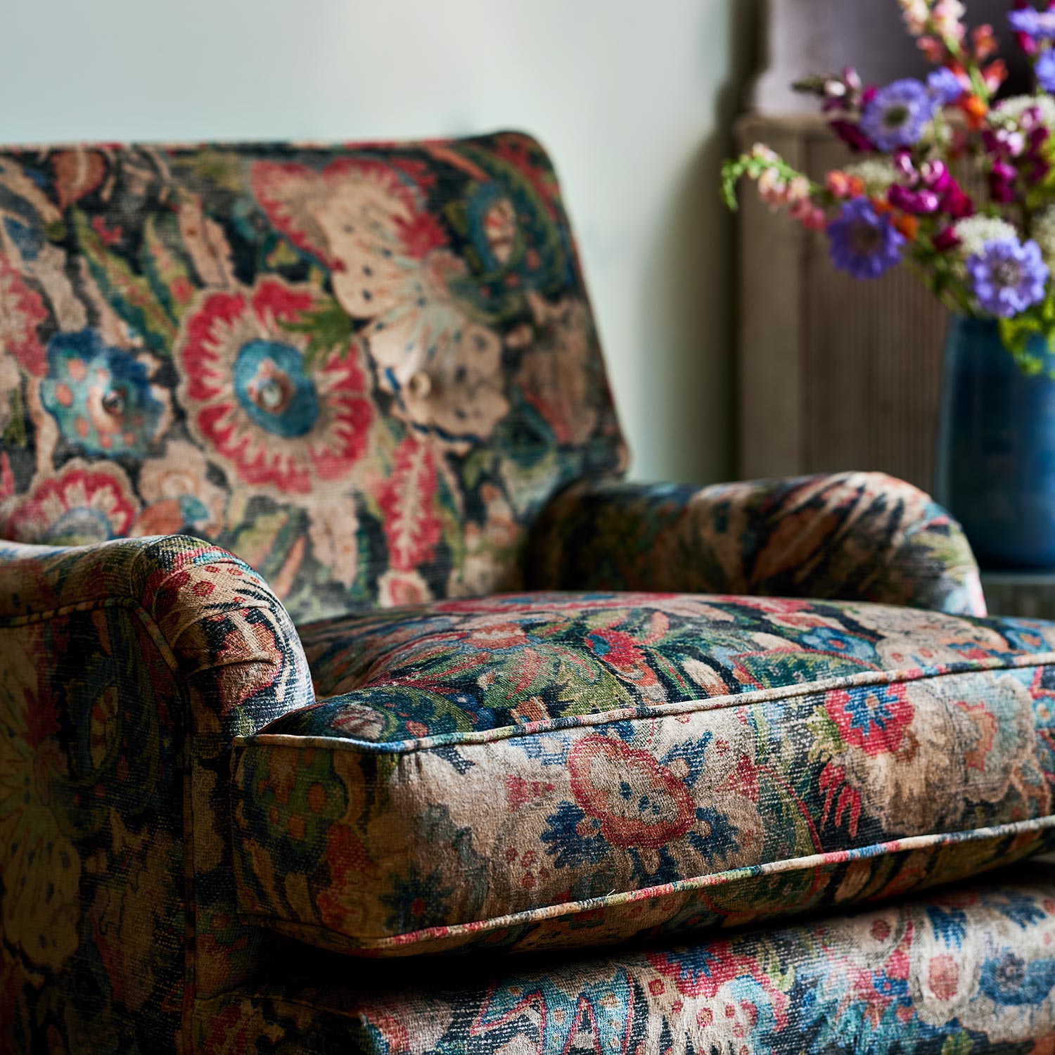 Armchair in a multicoloured printed velvet fabric featuring large, asymmetrical leaves and flowers.