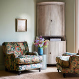 Two chairs in a multicoloured printed velvet fabric featuring large, asymmetrical leaves and flowers.