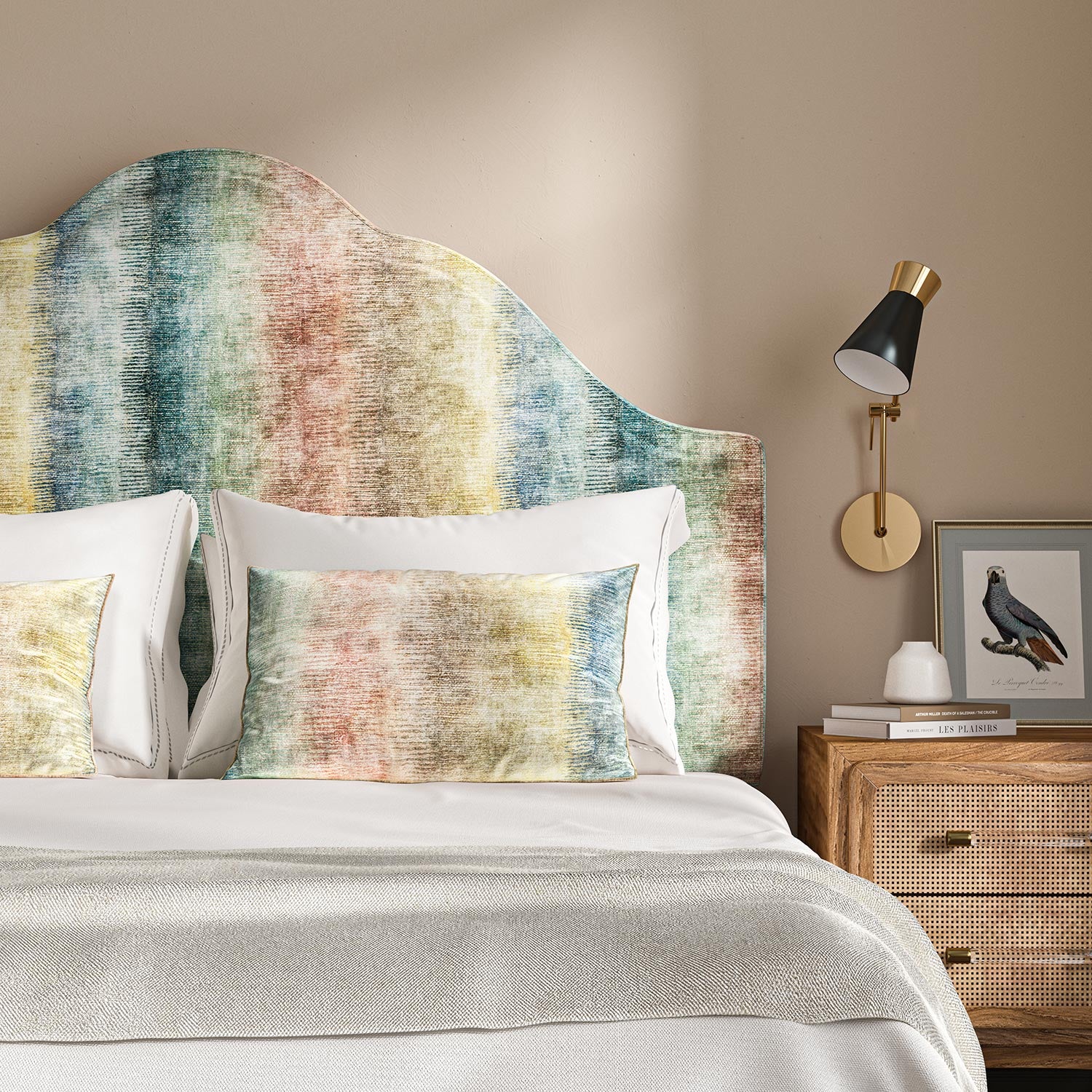 An upholstered headboard in a multicoloured printed velvet with pastel stripes.