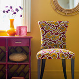 Chair upholstered in a woven velvet fabric sample in red, yellow and brown featuring a stylised cloud pattern.