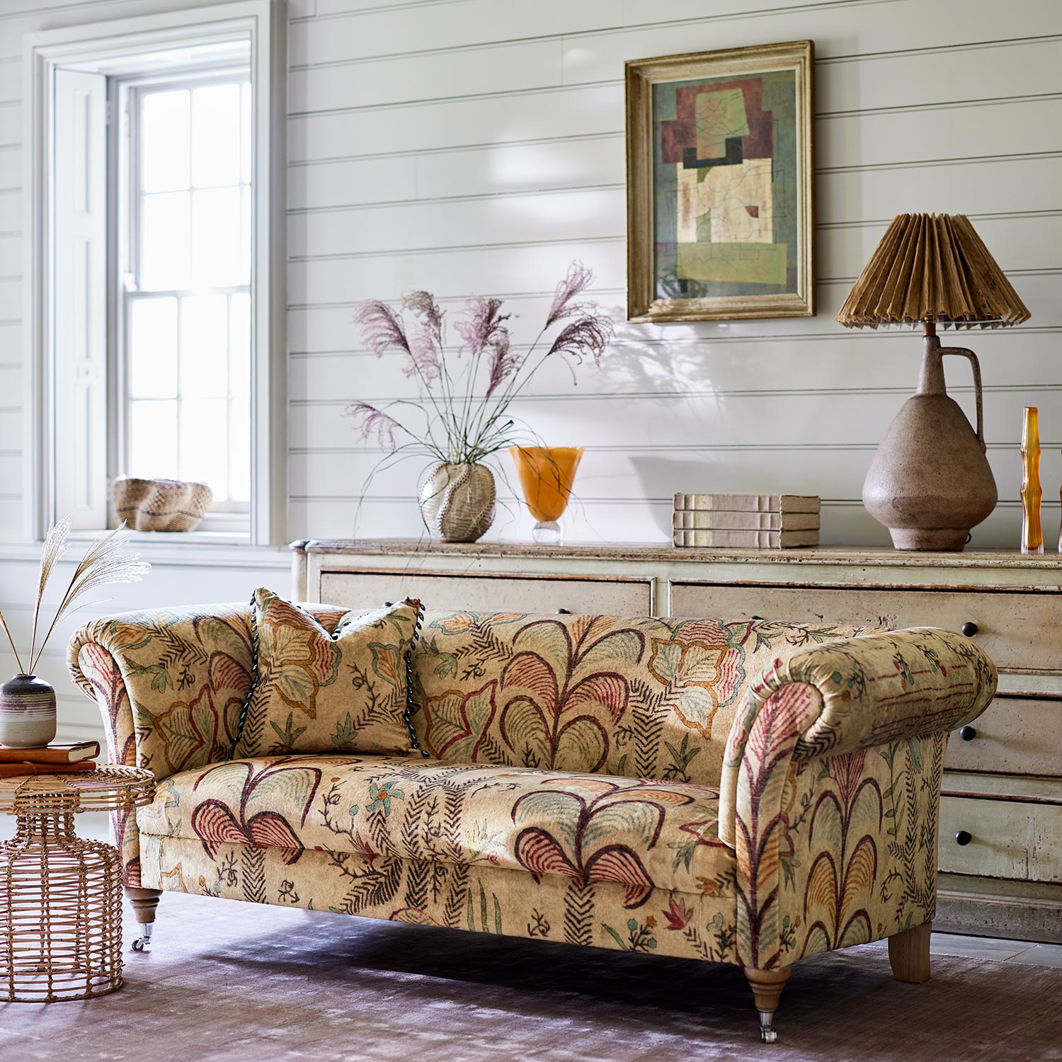 Sofa upholstered in a distressed printed velvet fabric with palms in sandy and red tones