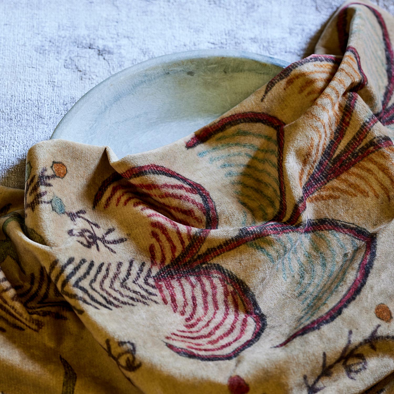 A distressed printed velvet fabric sample with palms in sandy and red tones