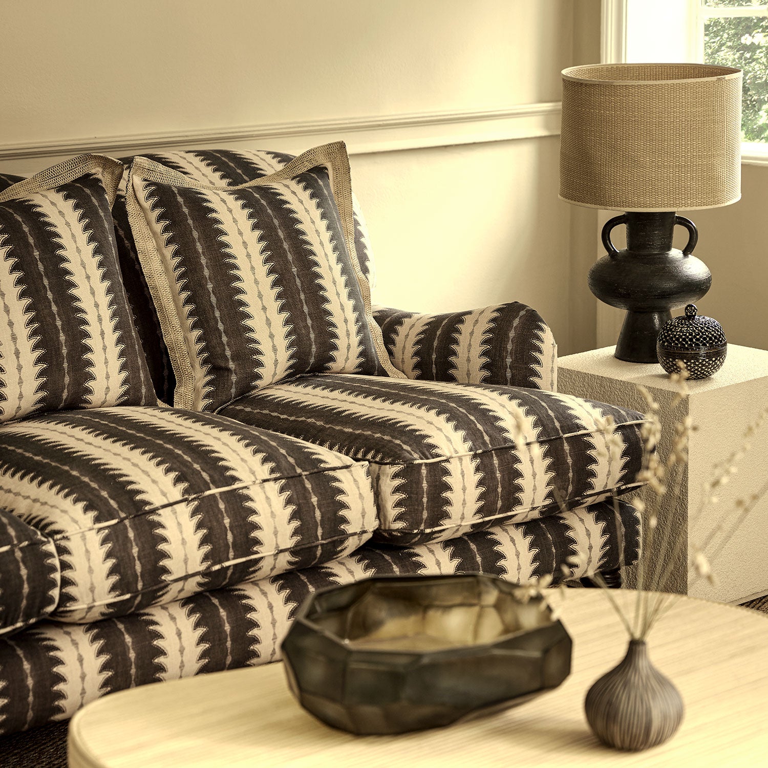 Sofa upholstered in a printed linen fabric in black and off white, featuring a striped fern design.