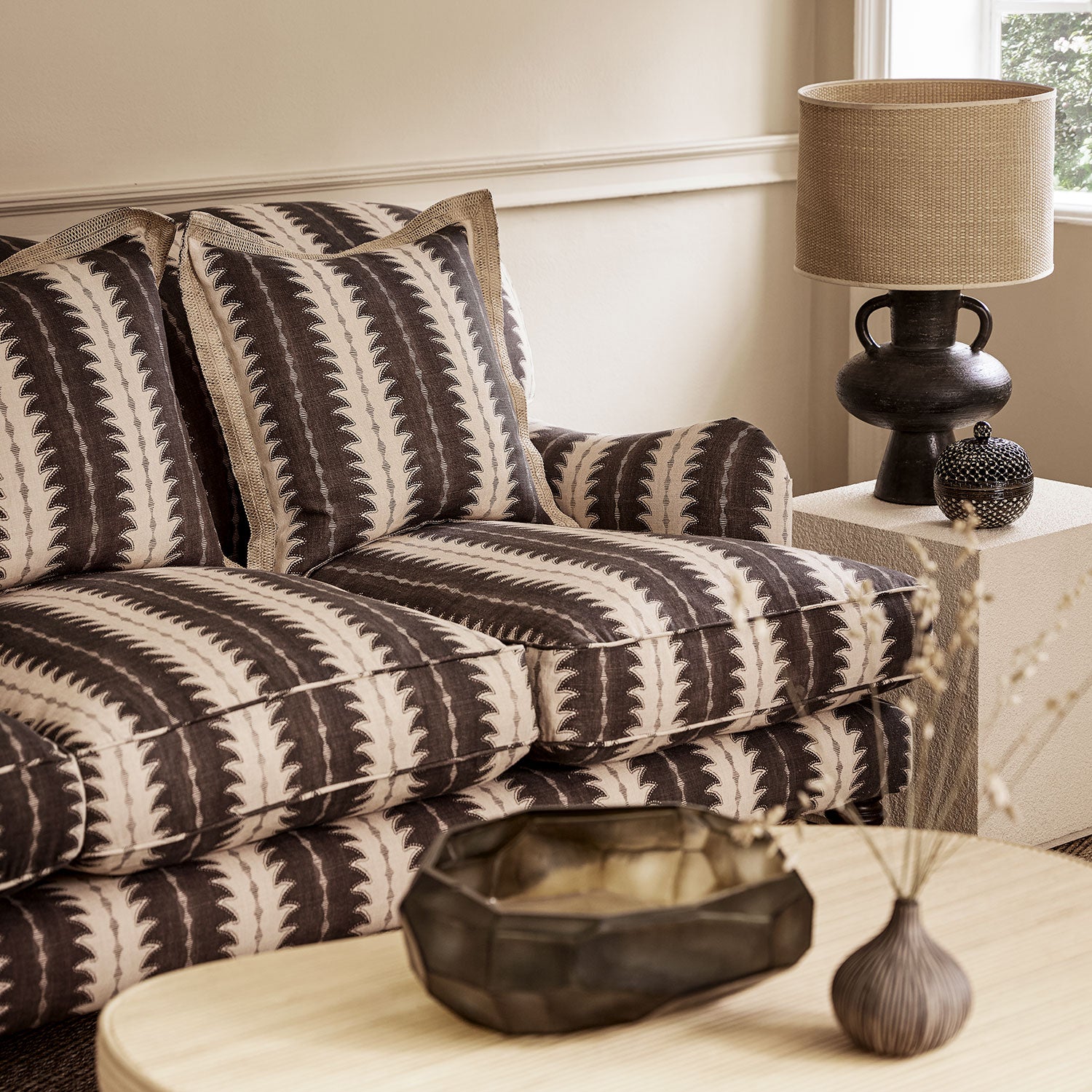 Sofa upholstered in a printed linen fabric in black and off white, featuring a striped fern design.