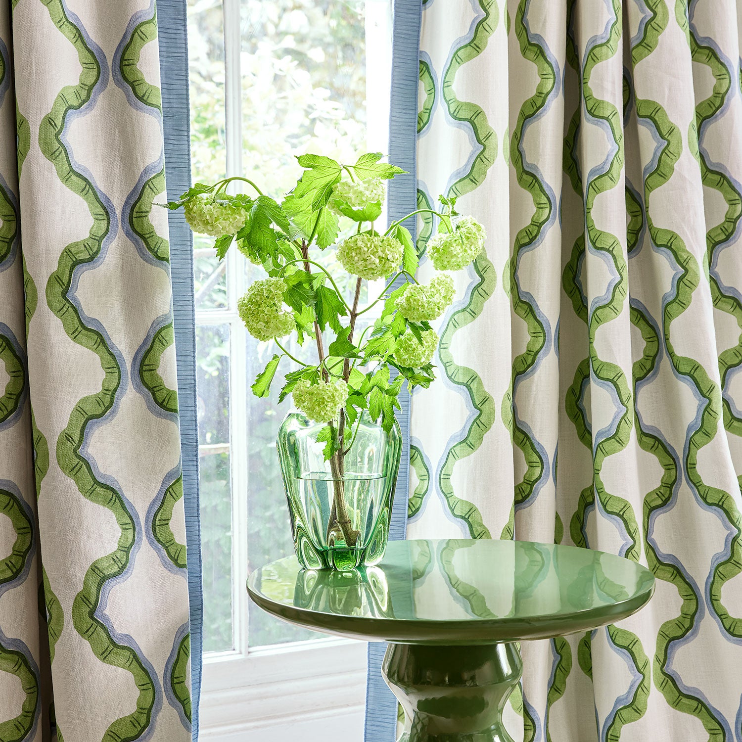 Curtains made from a printed linen fabric in blue, green, and off white featuring a mirrored ribbon pattern.