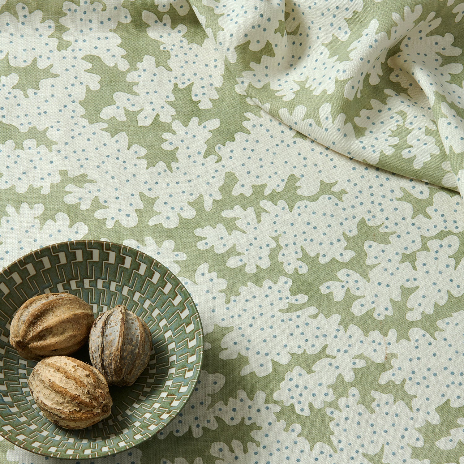 A printed linen fabric sample in green, blue and off white featuring a stylized coral pattern.