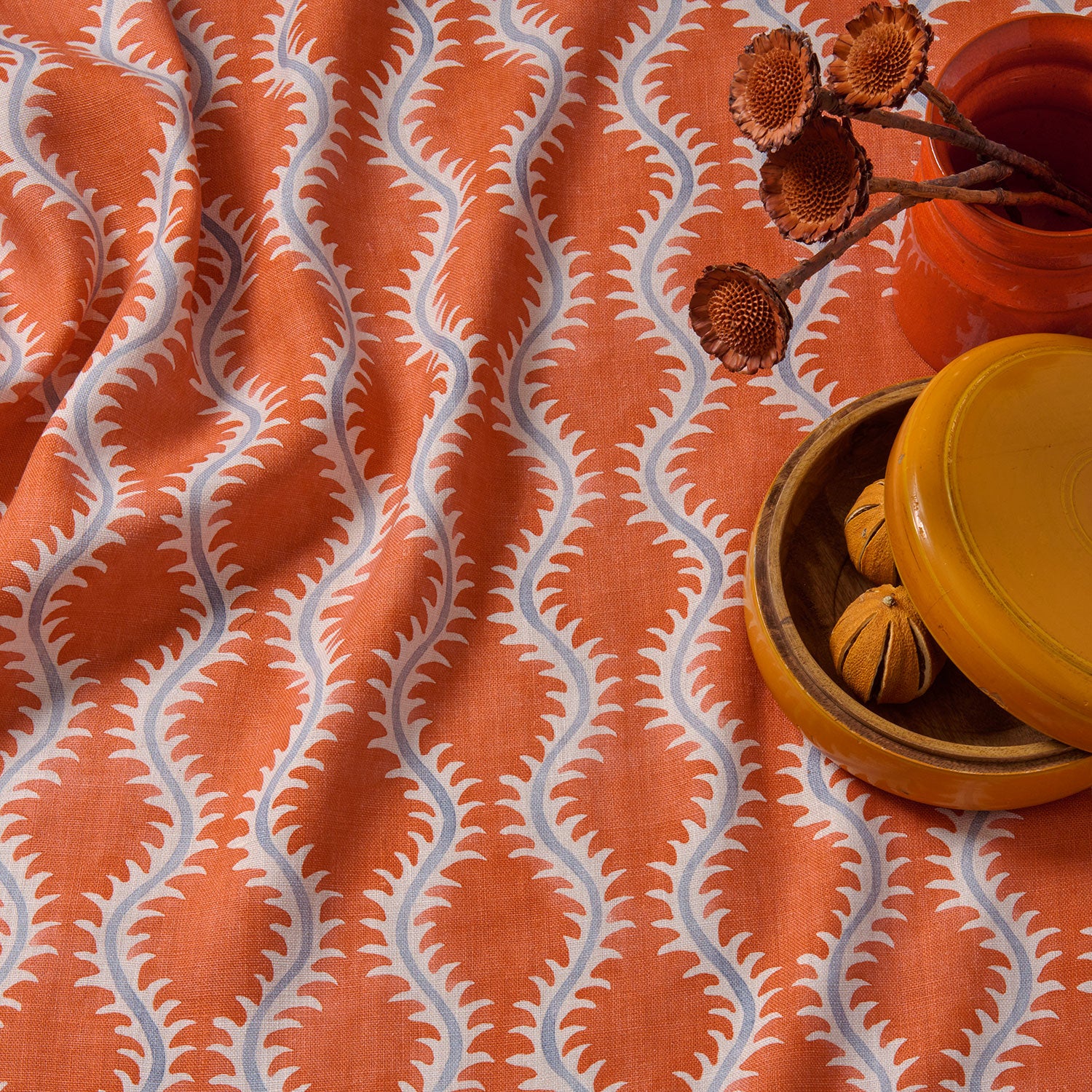 A printed linen fabric sample in blue and orange featuring a stylized fern pattern.