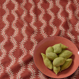 A printed linen fabric sample in red and pink featuring a stylized fern pattern.