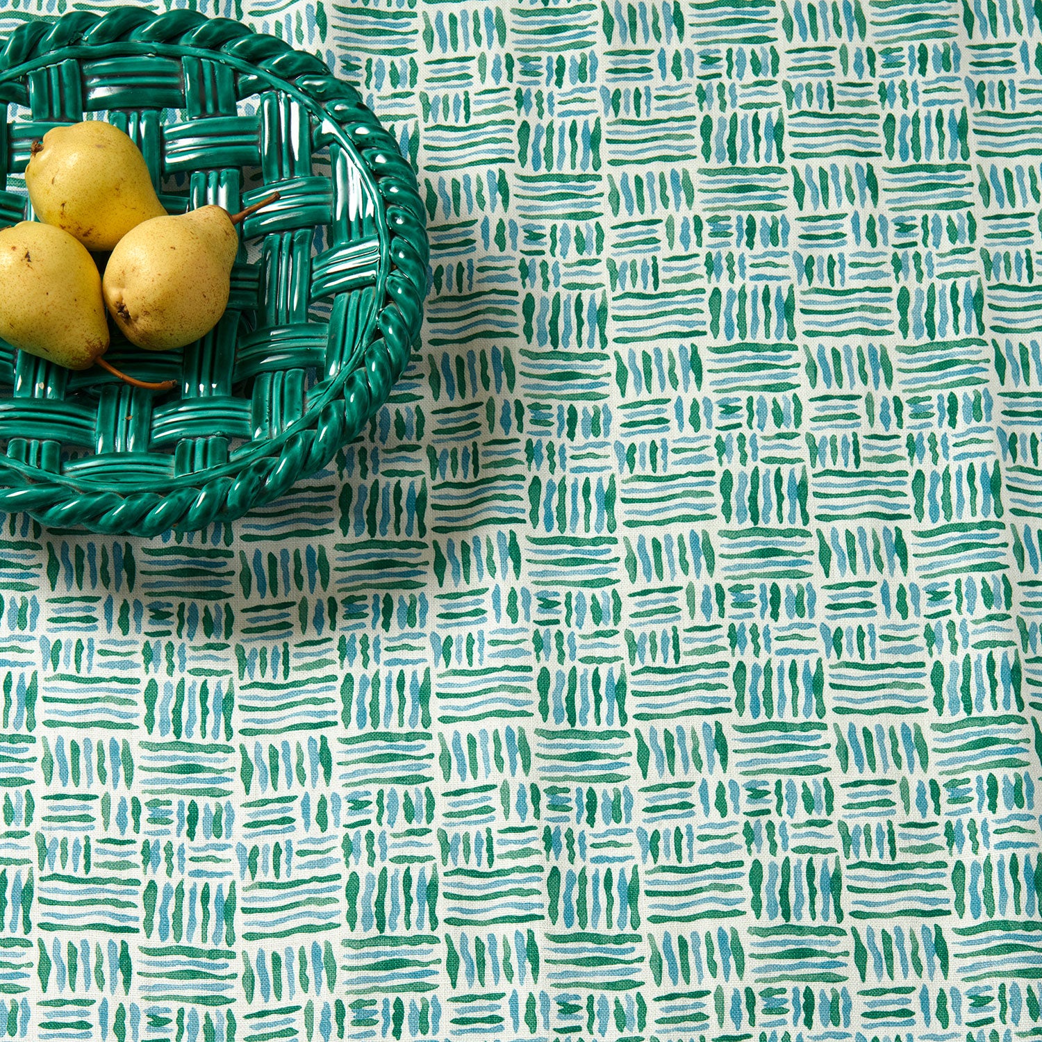 A printed linen fabric sample in blue, green and off white featuring a basketweave pattern.