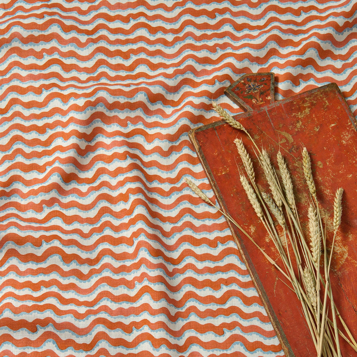 A printed linen fabric sample in red, blue and off white featuring a sound wave pattern