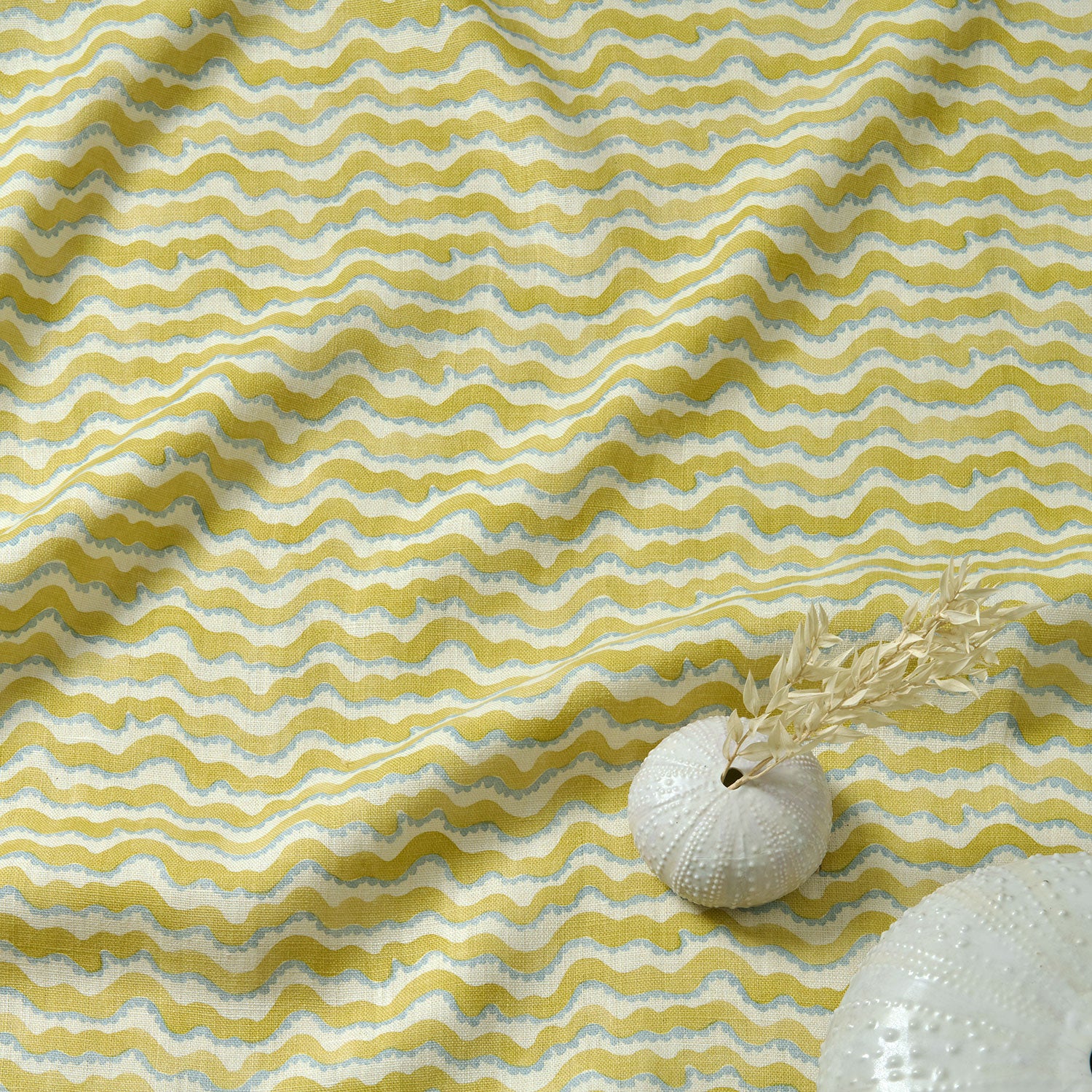 A printed linen fabric sample in yellow, blue and off white featuring a sound wave pattern