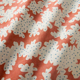 A printed linen fabric sample in orange, blue and off white featuring a stylized coral pattern.