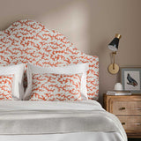 Headboard upholstered in a printed linen fabric sample in orange, blue and off white featuring a stylized coral pattern.