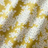 A printed linen fabric sample in yellow, blue and off white featuring a stylized coral pattern.