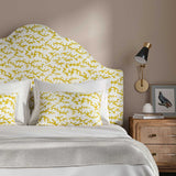 Headboard upholstered in a printed linen fabric sample in yellow, blue and off white featuring a stylized coral pattern.