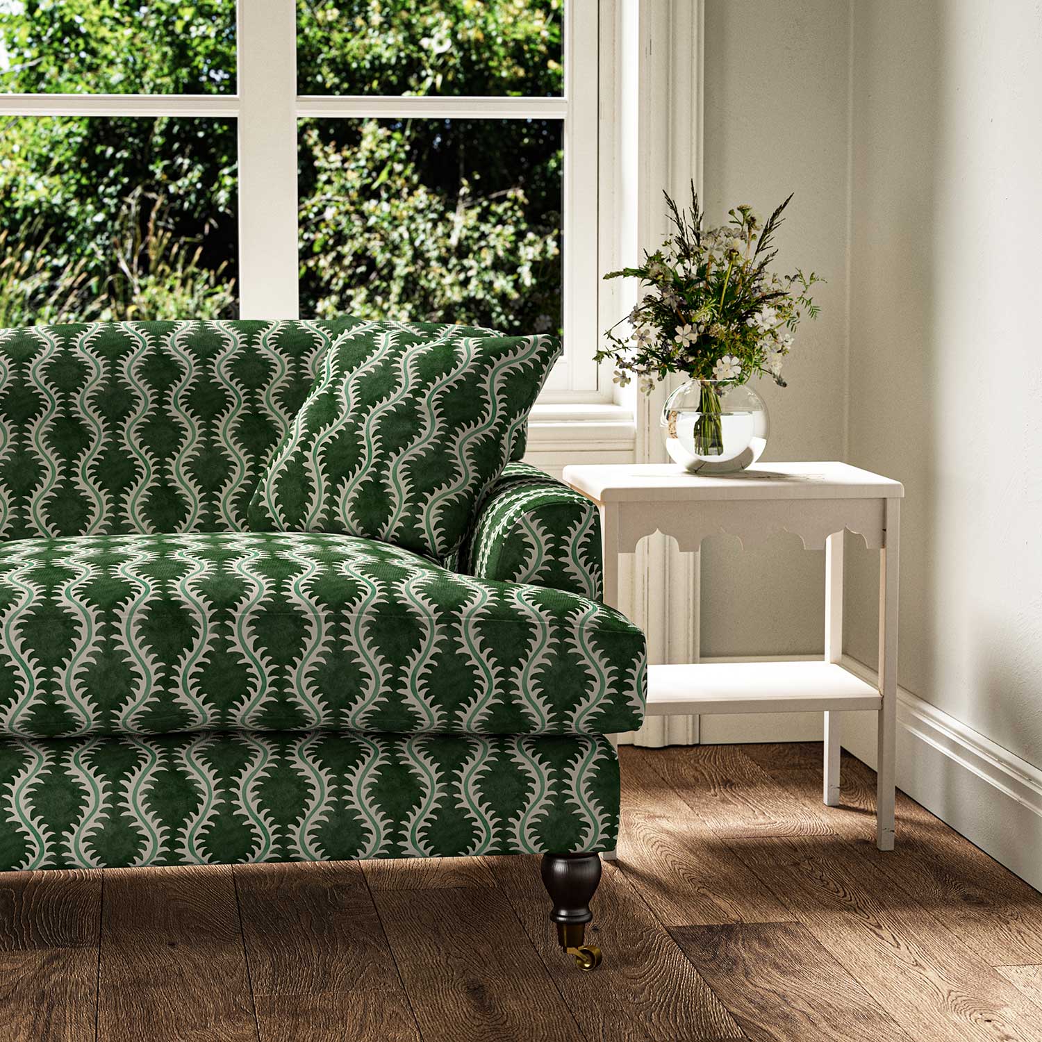 Sofa upholstered in a printed linen fabric sample in green and off white featuring a stylized fern pattern.