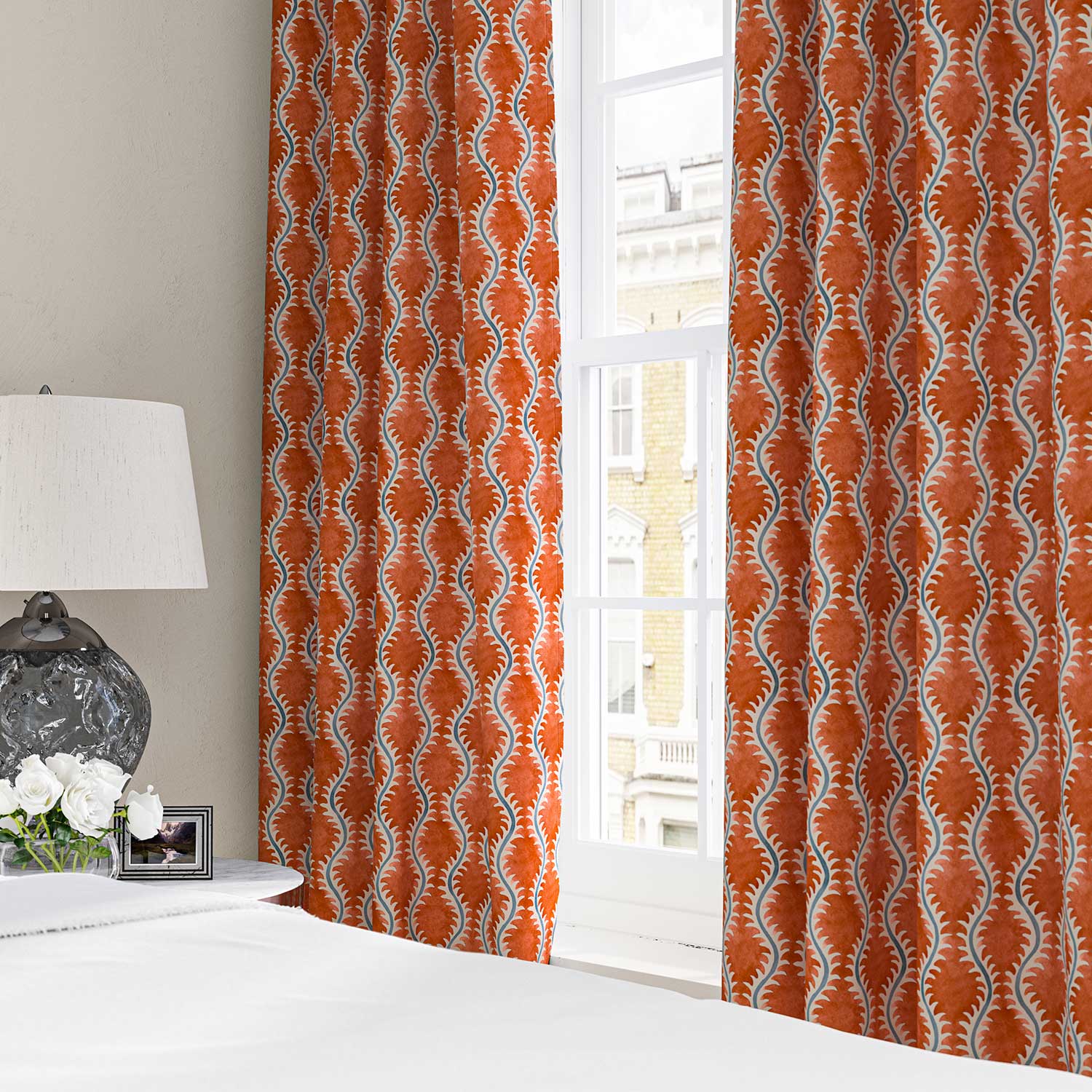 Curtains made from a printed linen fabric sample in blue and orange featuring a stylized fern pattern.