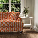 Sofa upholstered in a printed linen fabric sample in blue and orange featuring a stylized fern pattern.
