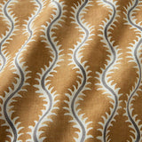 A printed linen fabric sample in orange, blue  and off white featuring a stylized fern pattern.