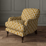 Chair upholstered in a printed linen fabric sample in orange, blue and off white featuring a stylized fern pattern.