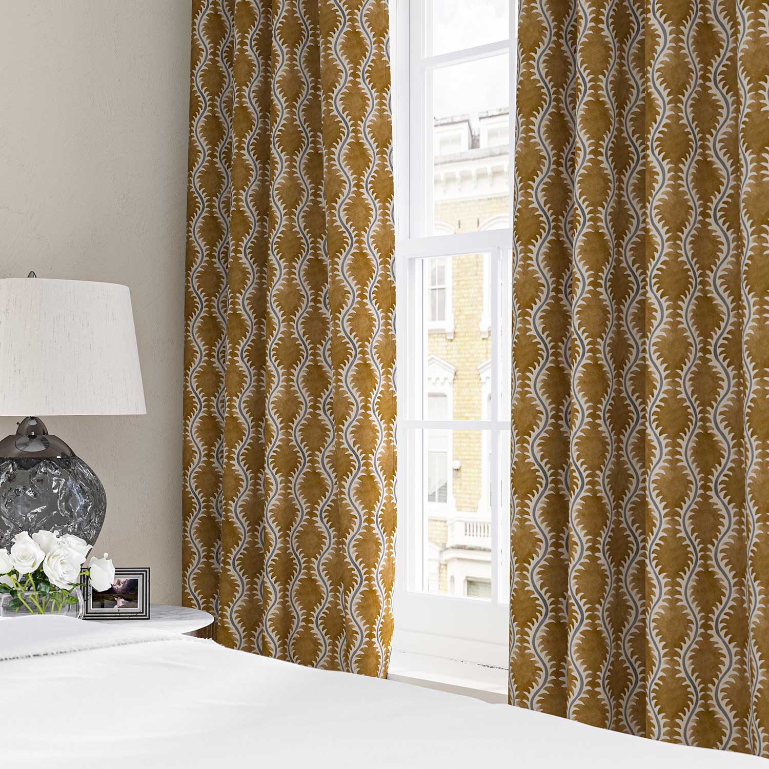 Curtains made from a printed linen fabric sample in orange, blue and off white featuring a stylized fern pattern.
