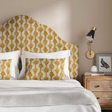 Headboard upholstered in a printed linen fabric sample in orange, blue and off white featuring a stylized fern pattern.
