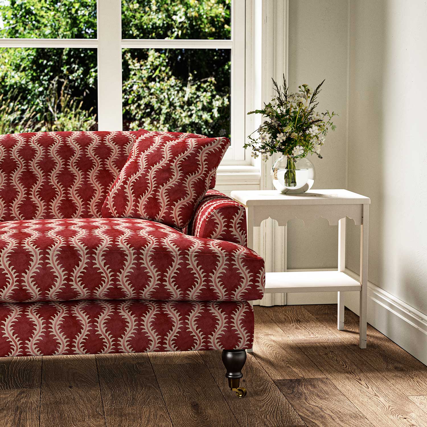 Sofa upholstered in a printed linen fabric sample in red and pink featuring a stylized fern pattern.