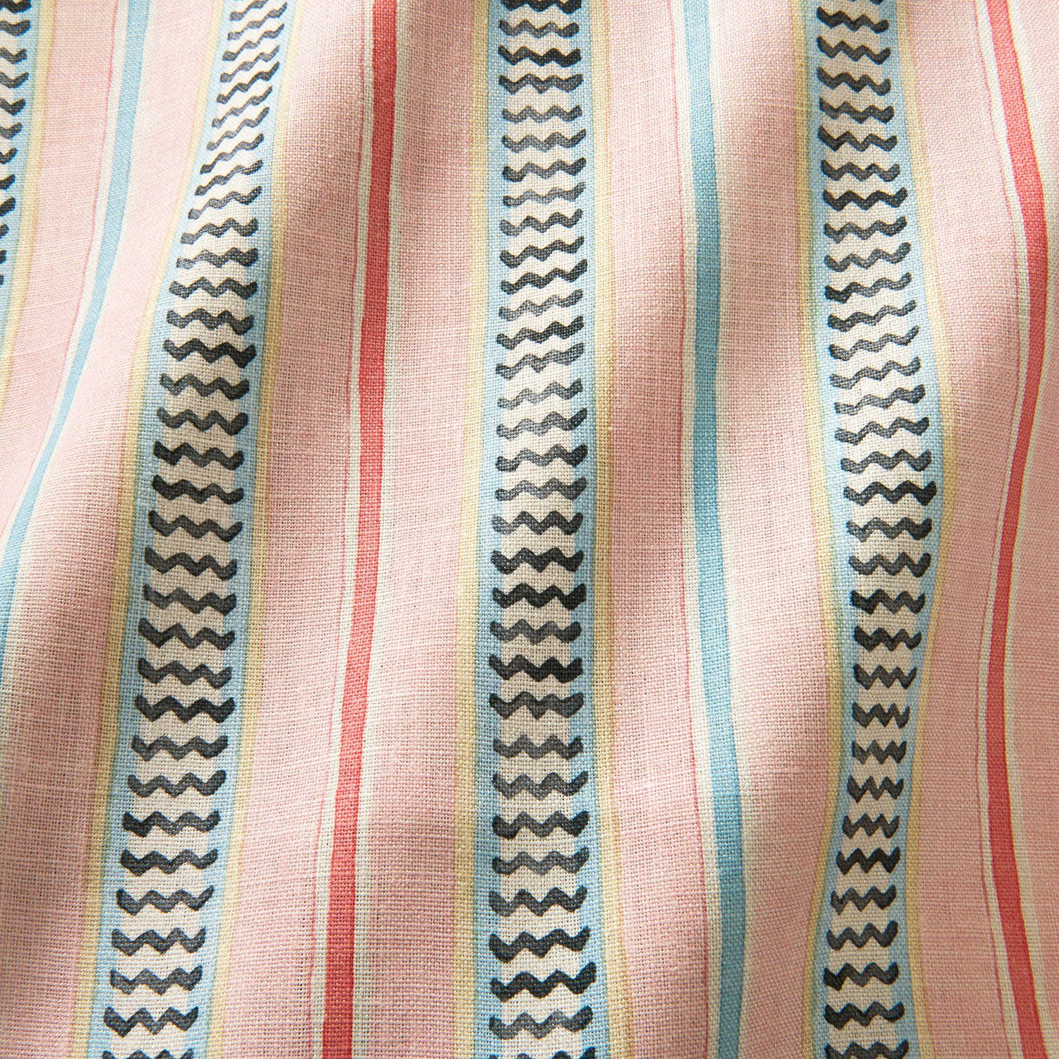A multicoloured – pink, red and blue – printed linen fabric sample featuring stripes, wavy edges and zigzags.